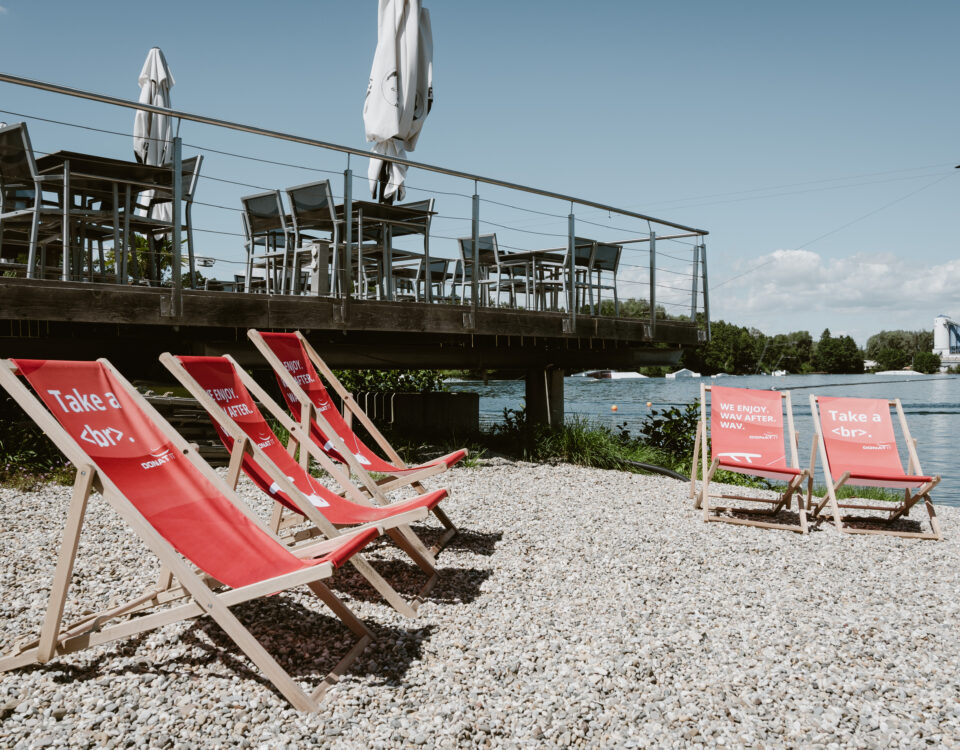 Liegestühle im DONAT IT Design auf der Wake & Groove Anlage mit Aussicht auf den See.